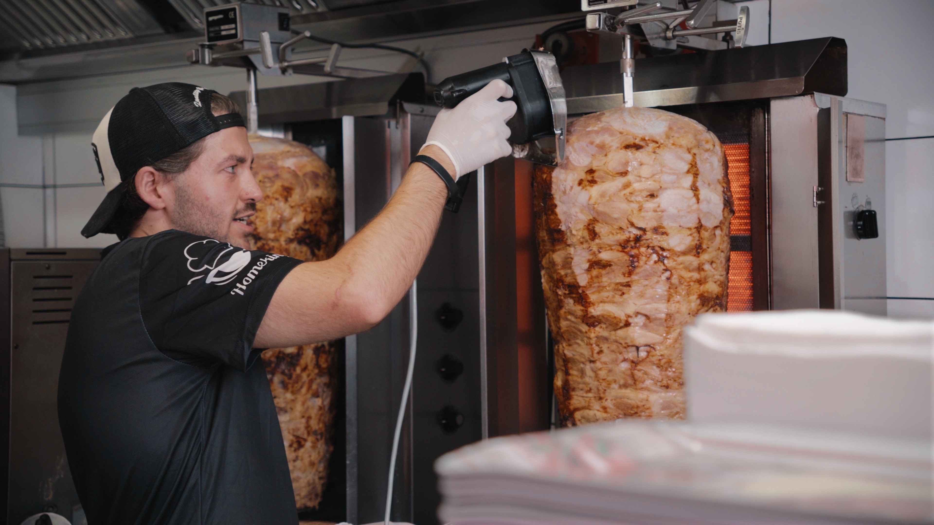 Mitarbeiter schneidet Fleisch vom Drehspieß bei Oski’s.